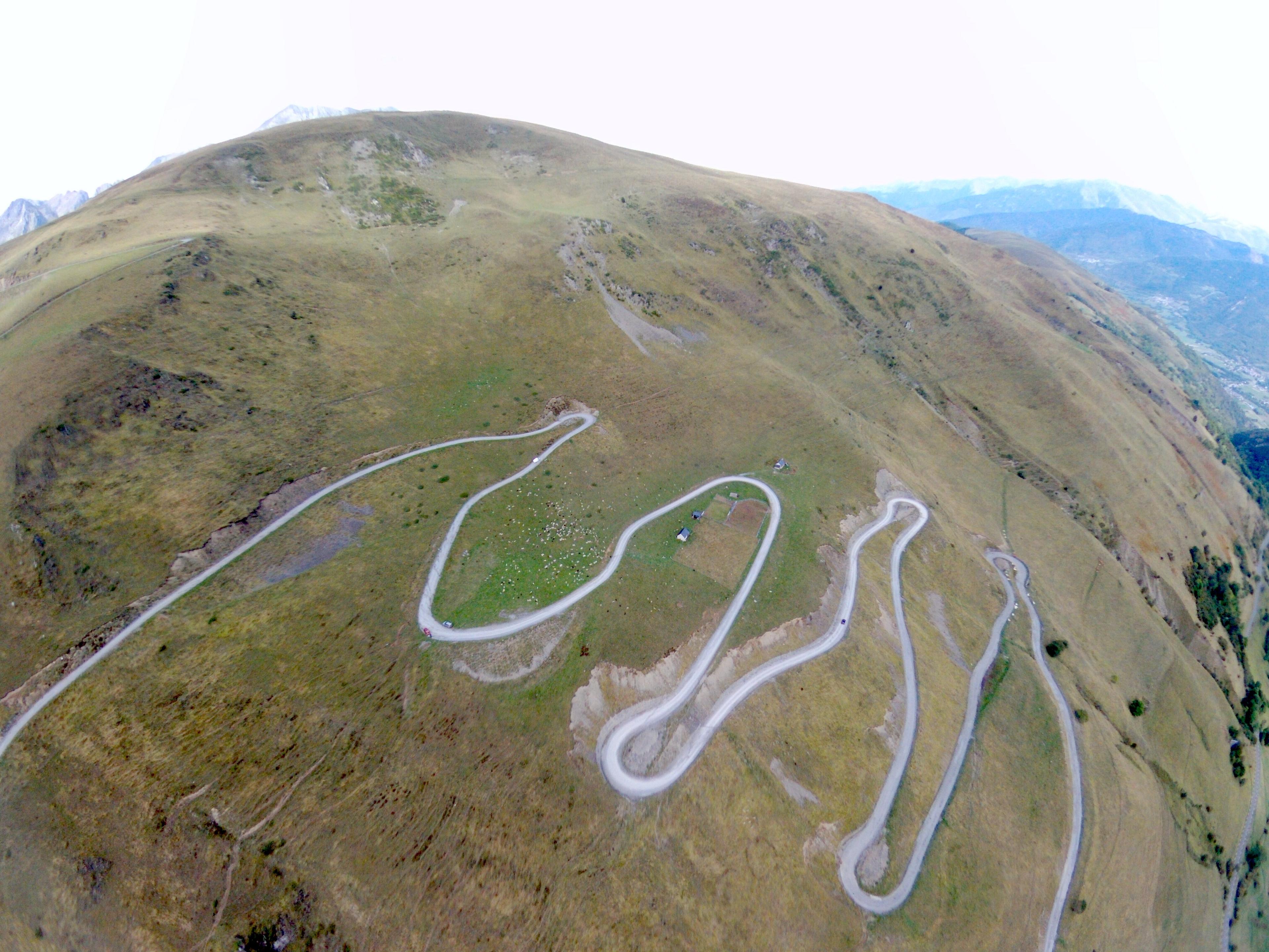 An aerial view of the Col du Portet road winding through open mountain pasture