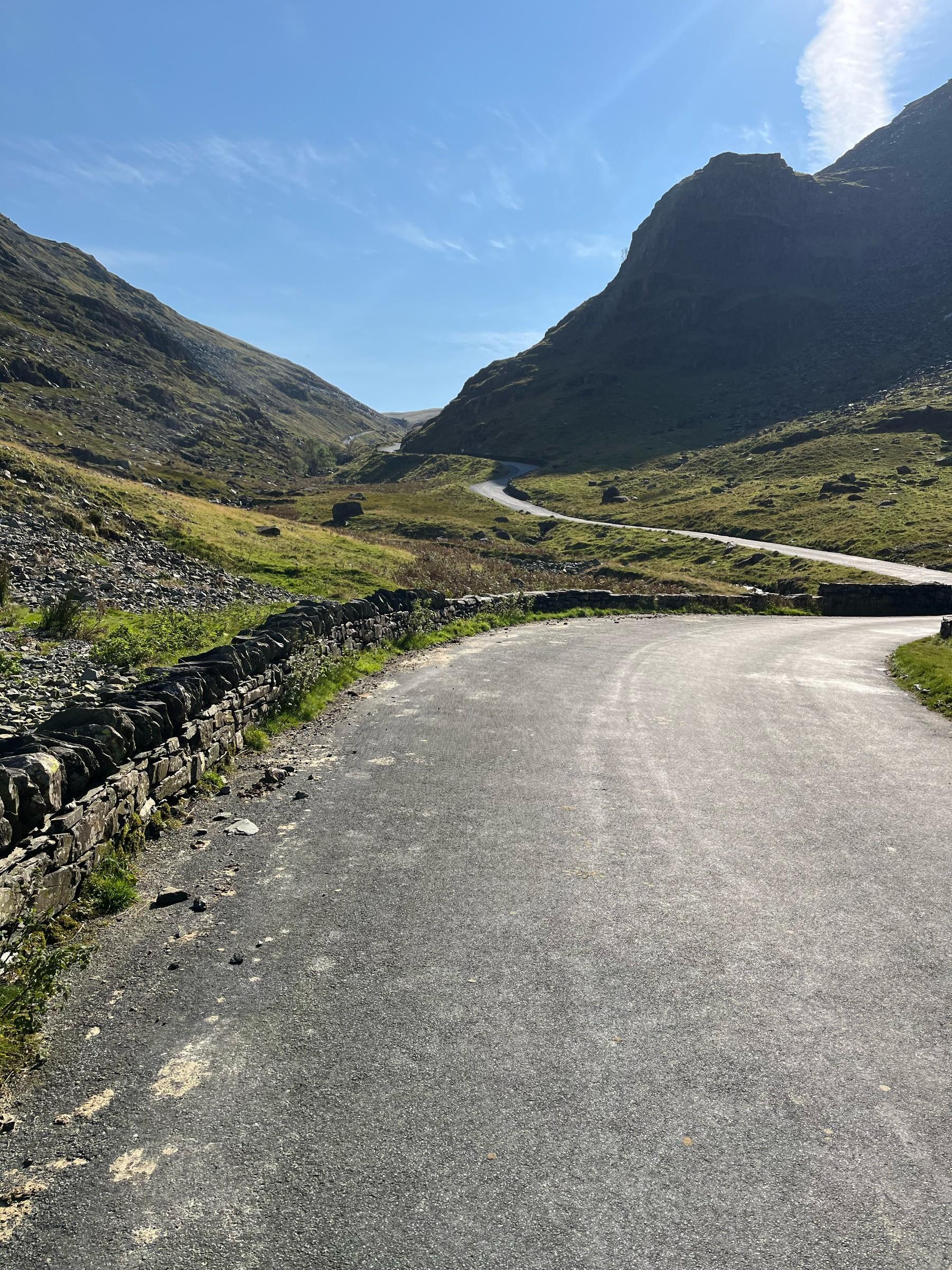 A winding road beneath the steep rocky slopes of Honister Pass