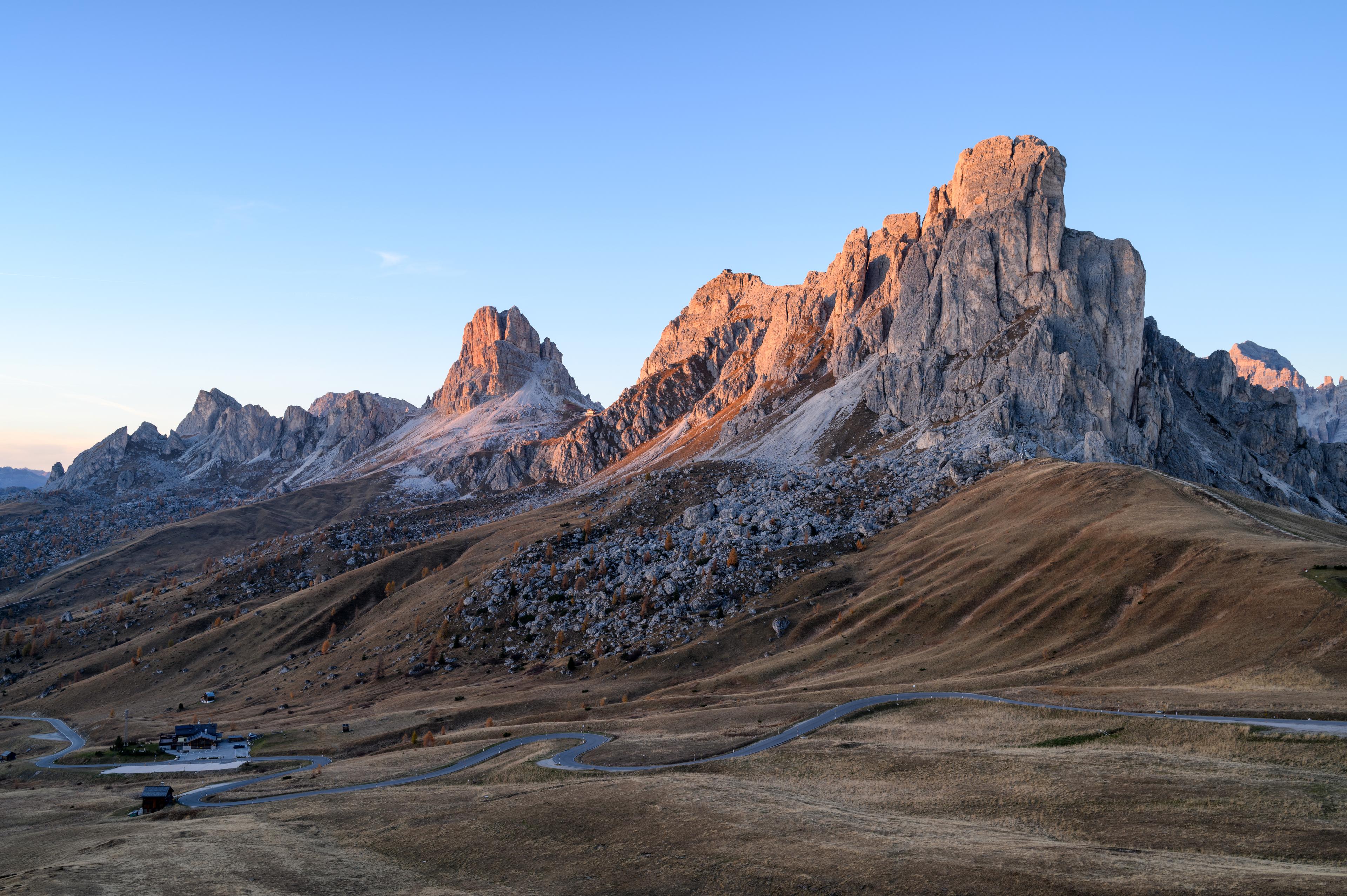 The road at Passo Giau beneath pale rock towers in warm evening light