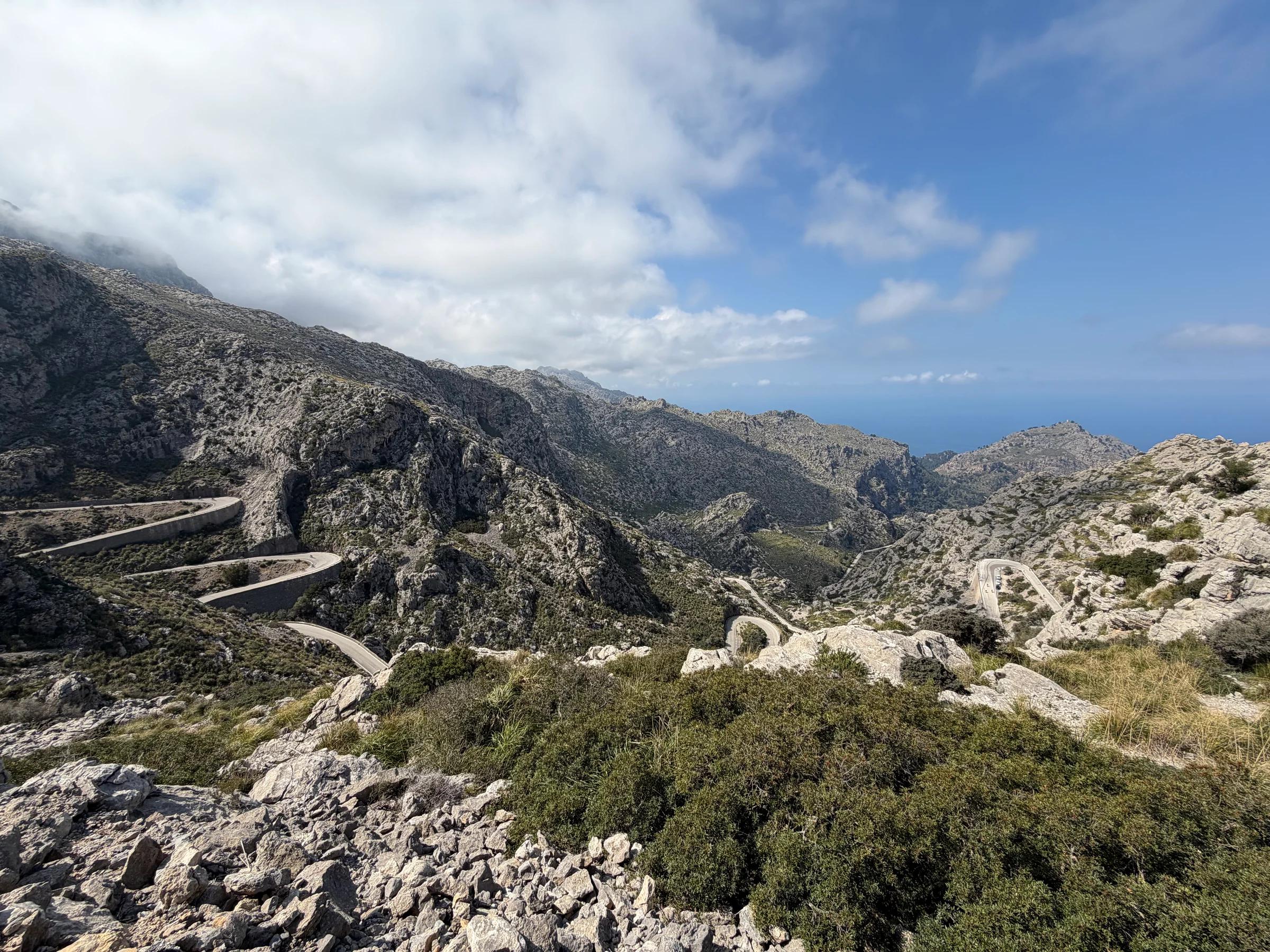 Hairpin bends winding through rocky mountains with the sea in the distance