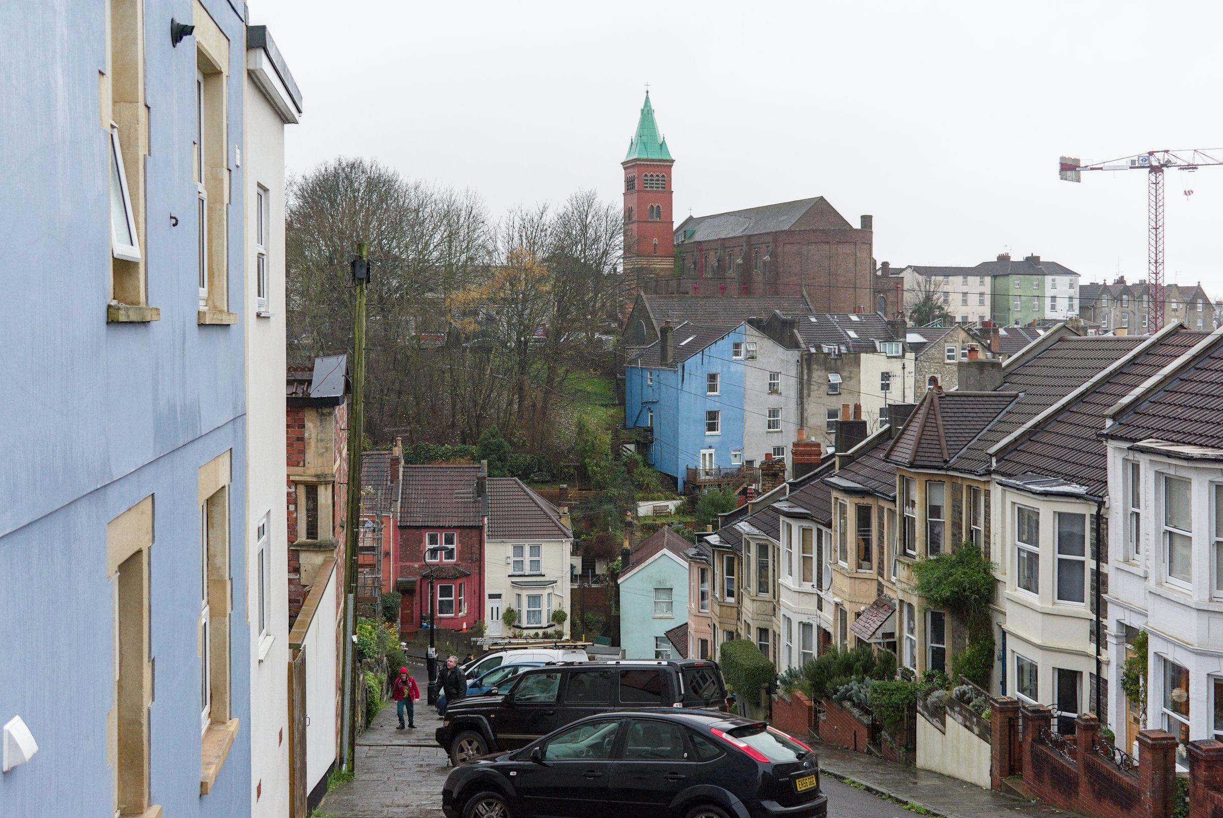 View down Vale Street between terraced houses and diagonally parked cars in Bristol