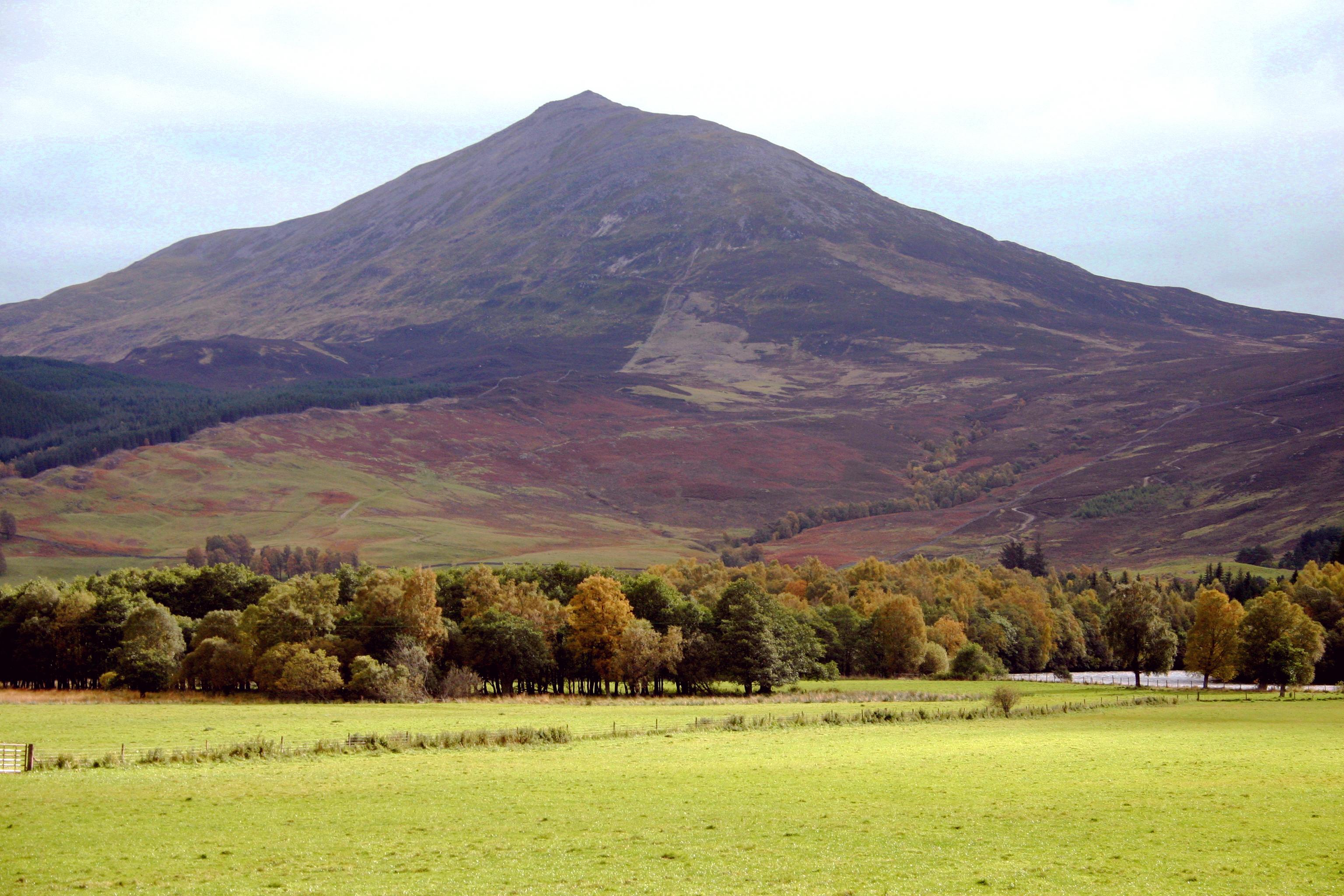 Schiehallion rising above autumn woodland and fields across the River Tay